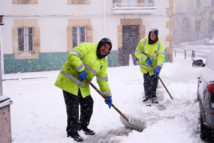 Archivo - Dos hombres quitan con palas la nieve del suelo