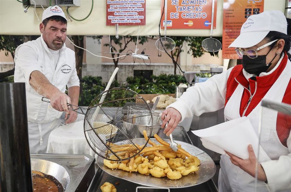 Archivo - Dos trabajadores hacen churros y buñuelos en las Fallas 2022