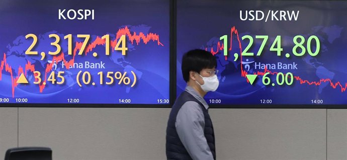 Archivo - 26 December 2022, South Korea, Seoul: A trader walks past a Hana Bank display showing the benchmark Korea Composite Stock Price Index (KOSPI), which rose 3.45 points, or 0.15 percent, to close at 2,317.14. Photo: -/YNA/dpa