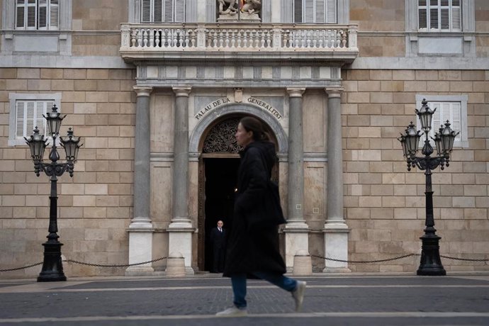Una persona pasea por delante del Palau de la Generalitat.