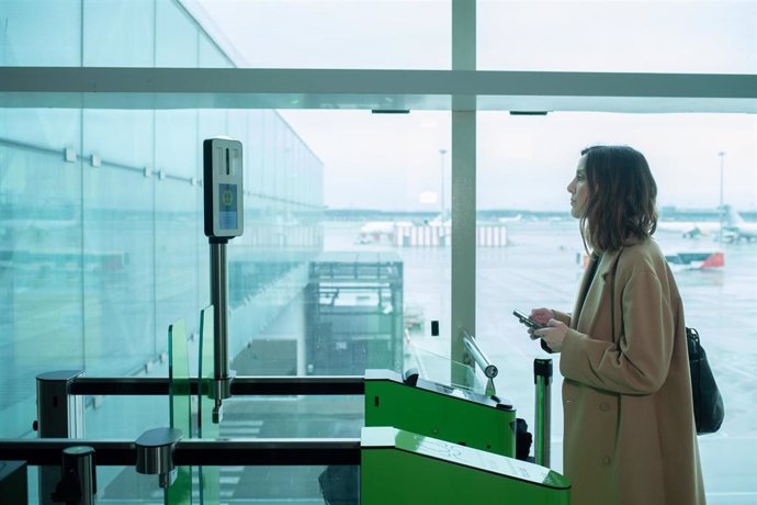 Archivo - Una mujer prueba el sistema de reconocimiento biométrico de Vueling, en el aeropuerto de El Prat