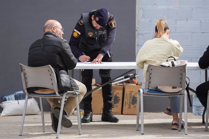 Afectats de l'incendi de l'edifici donen les seues dades a un agent de Policia Nacional, en els voltants de l'immoble, al barri de Campanar. 