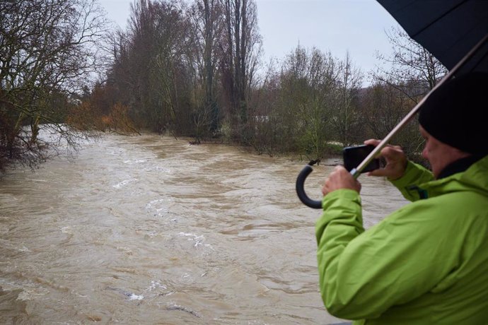Hombre toma una foto del río Arga en Pamplona, a 27 de febrero de 2024, en Pamplona, Navarra (España). Ante la previsión de precipitaciones a lo largo del día de hoy en la capital navarra, el Ayuntamiento de Pamplona ha activado el estado de preemergencia