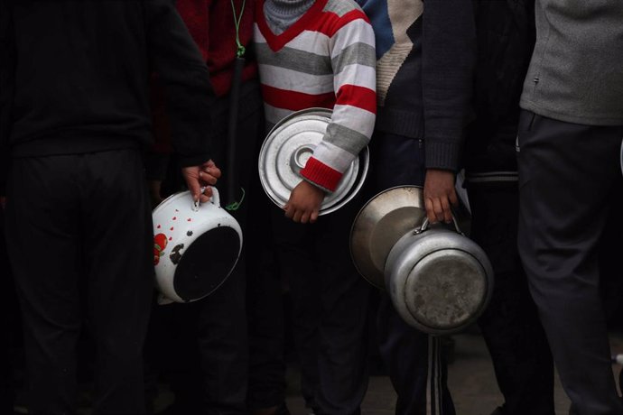 Niños palestinos esperando recibir alimentos distribuidos por organizaciones benéficas en Deir al Balá, en la Franja de Gaza