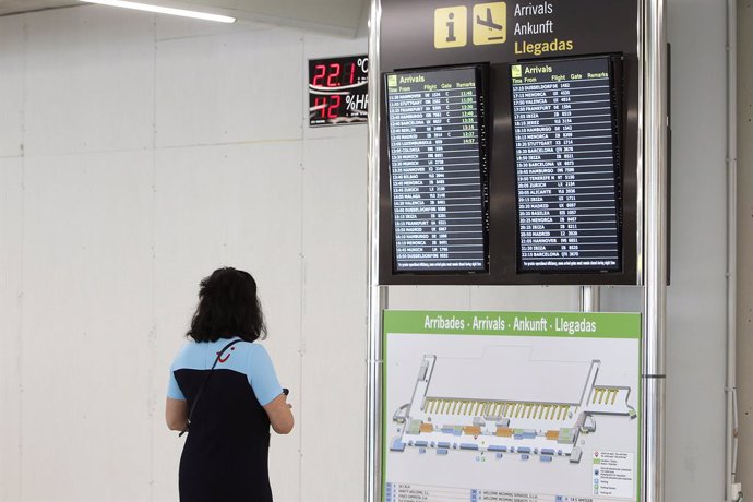 Archivo - Una pasajera observa la pantalla del aeropuerto de Palma.