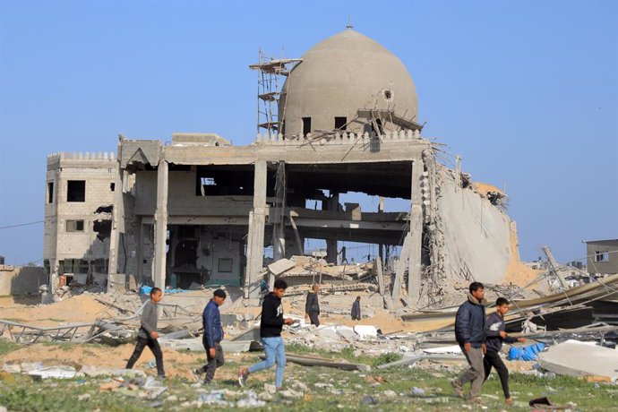 GAZA, Feb. 28, 2024  -- People walk past a destroyed building in the southern Gaza Strip city of Khan Younis, on Feb. 28, 2024. The Palestinian death toll in the Gaza Strip has risen to 29,954 as the Israeli military killed 76 in the past 24 hours, the Ha