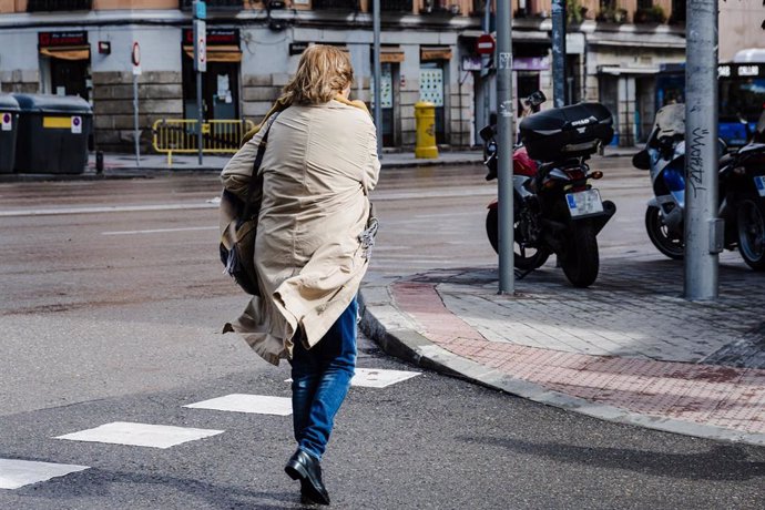 Archivo - Una mujer con el pelo y la chaqueta movidos por el viento en Madrid.