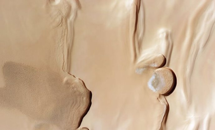 Esta imagen de la sonda espacial Mars Express de la ESA muestra el terreno que rodea el polo norte de Marte. Captura la región donde las vastas y ondulantes dunas de arena se encuentran con las capas de hielo polvoriento que cubren el polo del planeta