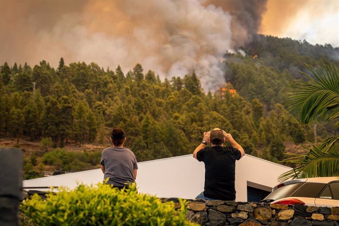 Archivo - Dos vecinos observan las llamas del incendio forestal declarado en  la Palma