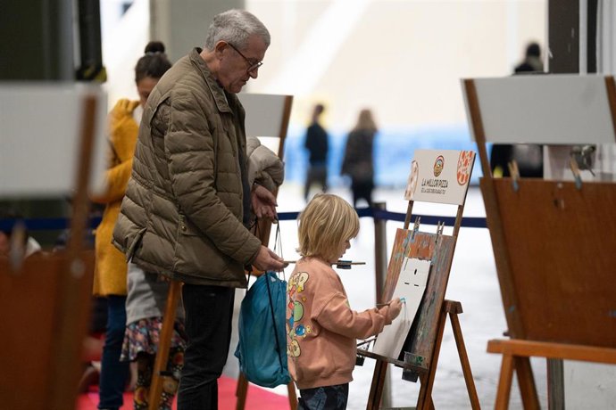 Archivo - Una niña realiza una actividad junto a su abuelo. ARCHIVO.