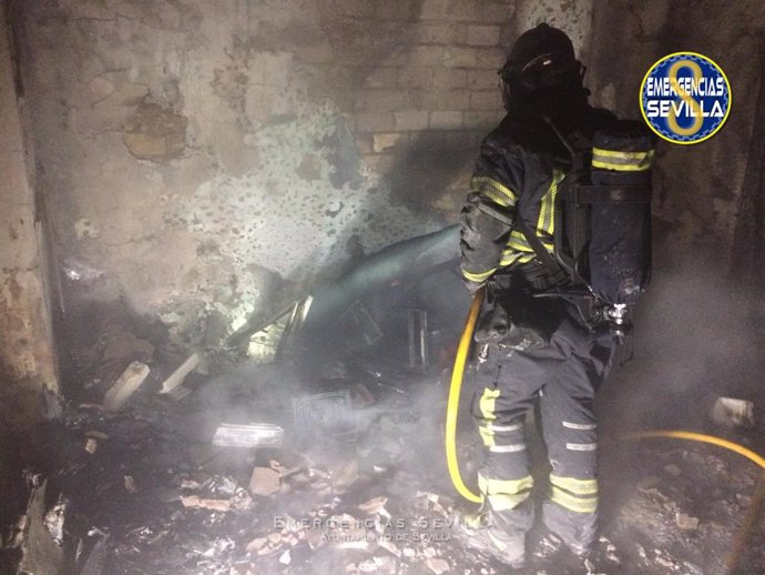 Un bombero realiza su trabajo en la vivienda incendiada del barrio de Torreblanca.