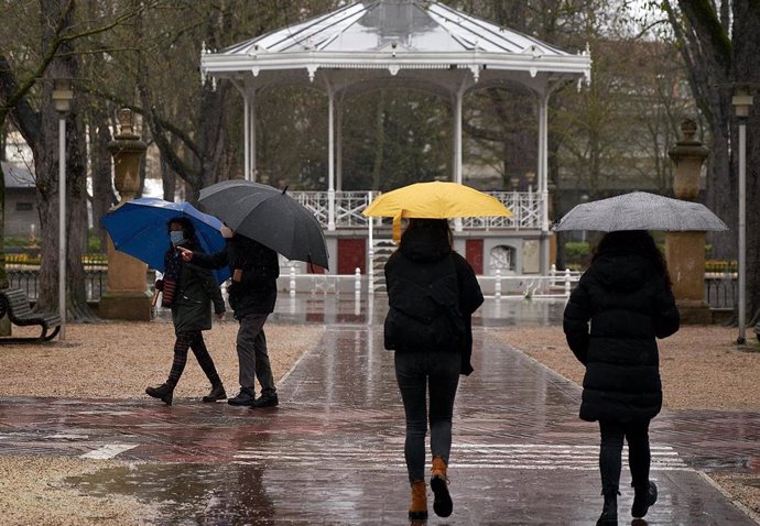Archivo - Varias personas se refugian con un paraguas de la lluvia en Vitoria