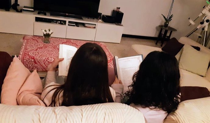 Mirella (izqda) y Diana (dcha) leen en el comedor de su casa, en Santa Cruz de Tenerife (España). Las dos hermanas cuentan a Europa Press cómo afrontan el 8 de marzo y cómo creen que se vivirá en el futuro