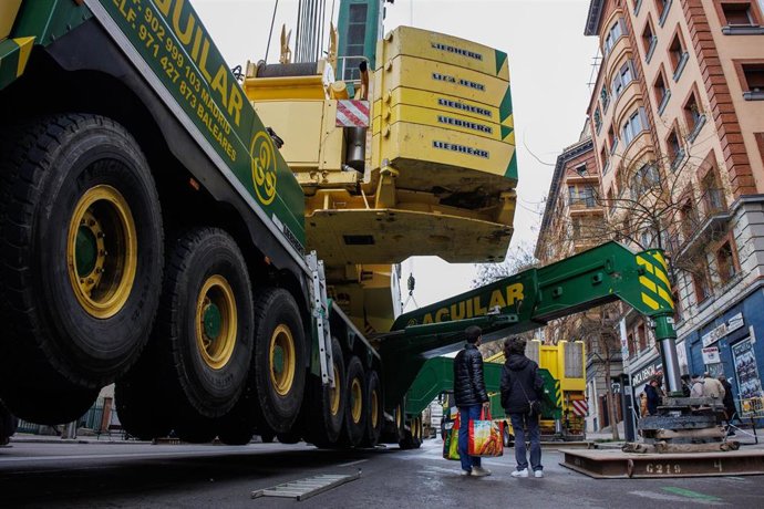 Dos personas observan una grúa junto a un edificio en la calle Cavanilles
