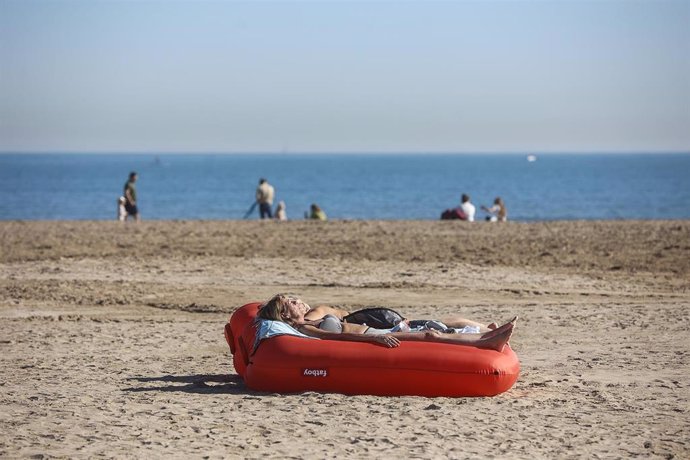 Archivo - Una mujer toma el sol tumbada en un flotador, en la playa de la Malvarrosa, a 25 de enero de 2024