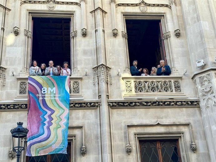 El conseller insular de Presidencia, Antoni Fuster, y la directora insular de Familias, María Garrido, acompañados de la directora de IBDona, Catalina Salom, cuelgan una banderola en la fachada del Palau del Consell para conmemorar el 8M