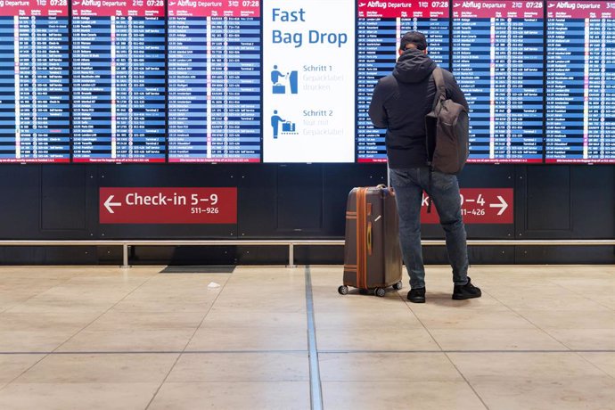 28 February 2024, Berlin: A passenger stands in front of a display board for departures in the hall of Terminal 1 at BER Airport. 