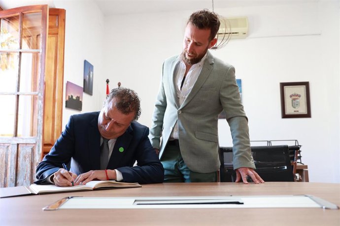 El presidente de la Diputación de Sevilla, Javier Fernández, firma en el Libro de Honor junto al alcalde de El Coronil, José López Ocaña, durante su visita institucional al Ayuntamiento.
