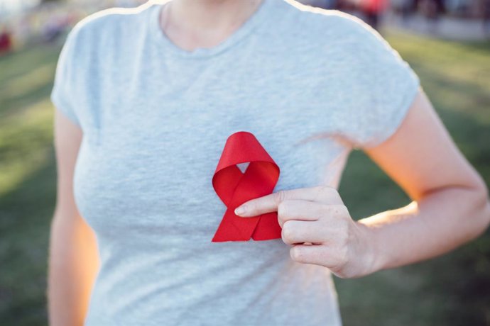 Archivo - Manos sosteniendo rojo cinta del conocimiento del sida
