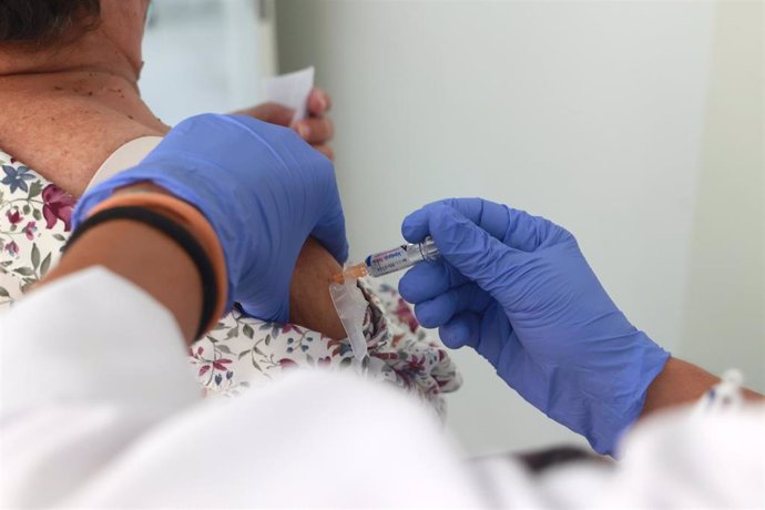 Archivo - Una mujer se vacuna contra la gripe y la covid en un centro de salud.