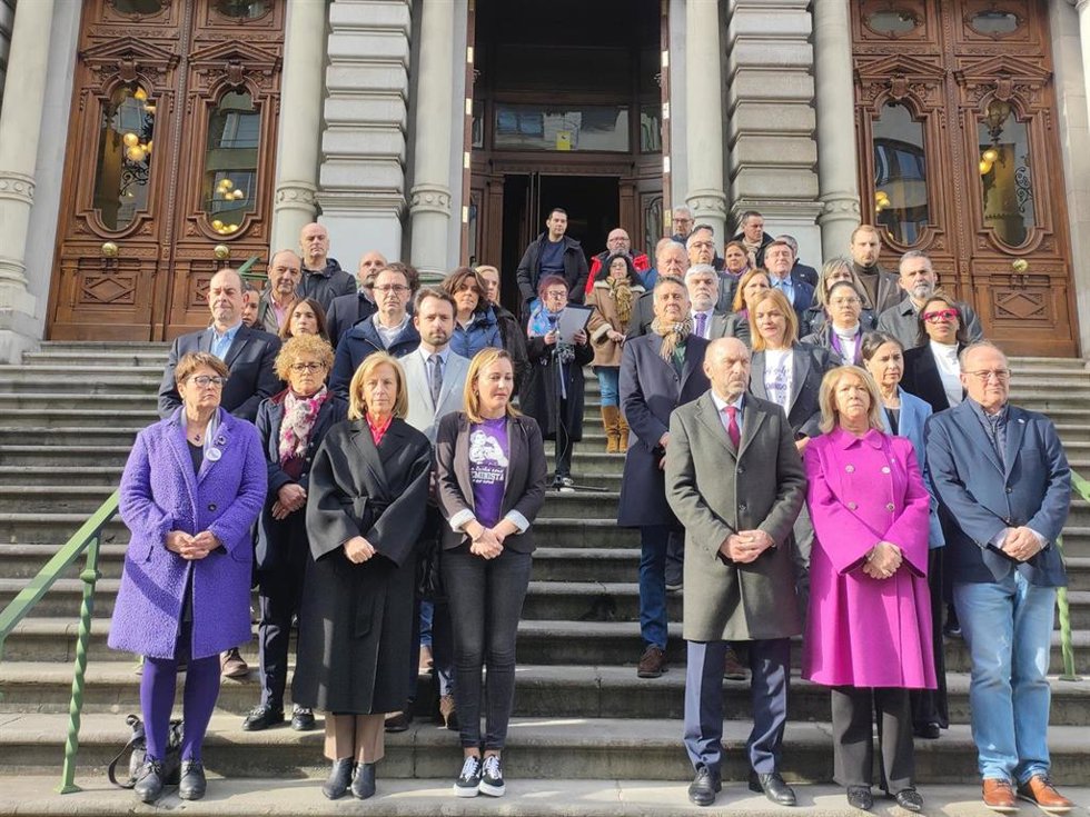 Diputadas y diputados de la Junta General en la lectura de la declaración de la Junta de Portavoces por el 8-M, leída por la recientemente jubilada archivera del parlamento, Josefina Velasco