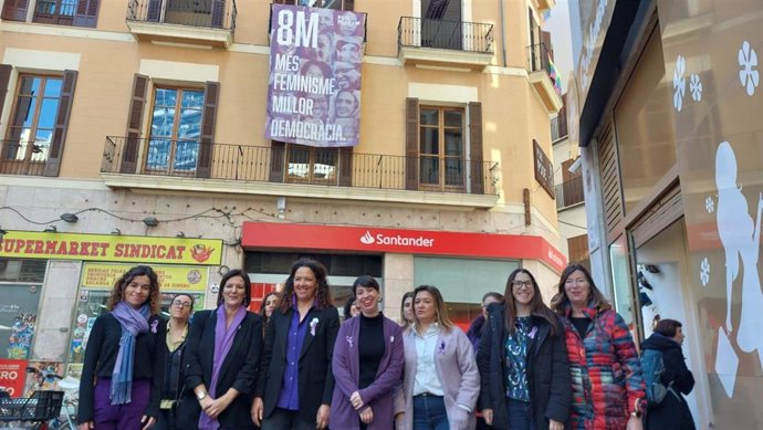 Representantes del PSIB tras desplegar una pancarta conmemorativa del 8M en la sede del partido de Palma.