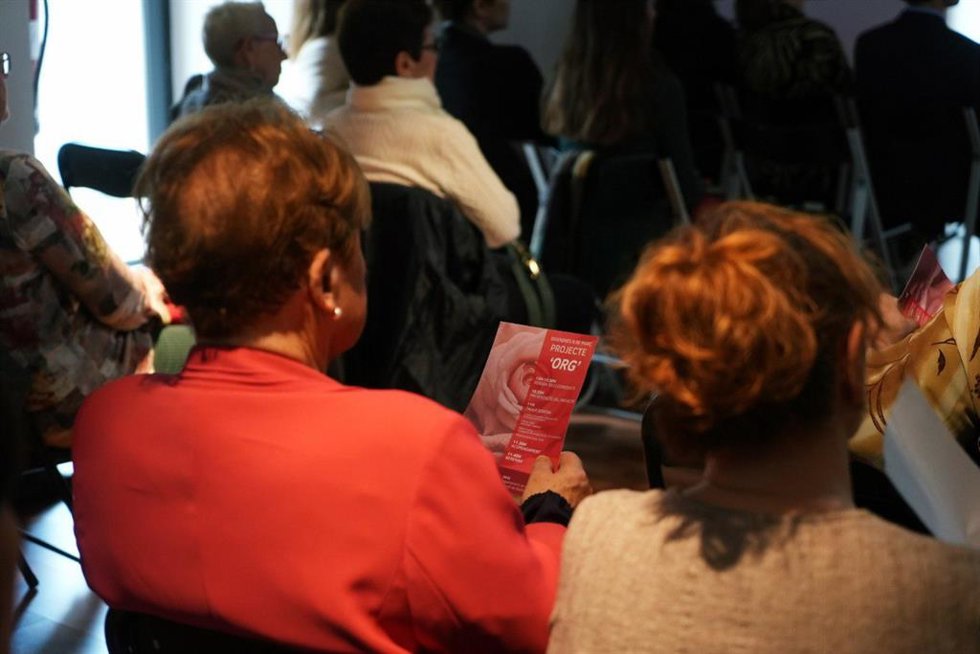 Una mujer sostiene el folleto del proyecto ORG presentado este viernes en Petra.