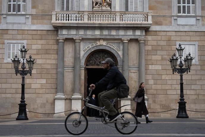 Una persona en bicicleta pasa por delante del Palau de la Generalitat, a 22 de febrero de 2024, en Barcelona, Catalunya (España). El Palau de la Generalitat es la sede de la Presidencia y del Gobierno de Cataluña. Se trata de uno de los pocos edificios 