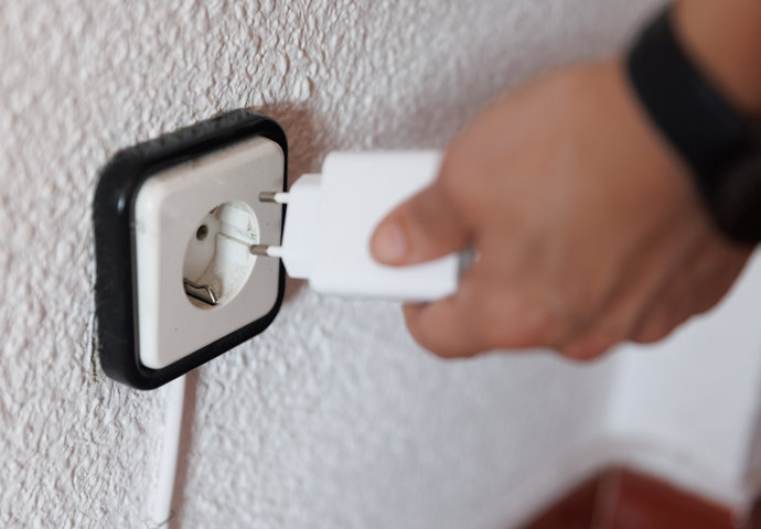 Una persona sujeta un cargador frente a un enchufe, a 14 de marzo de 2023, en Madrid (España).