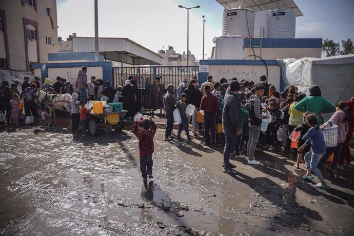 Un grupo de palestinos recoge agua en un punto de suministro en la Franja de Gaza, en medio de la escasez en medio de la ofensiva de Israel tras los ataques ejecutados el 7 de octubre por el Movimiento de Resistencia Islámica (Hamás)