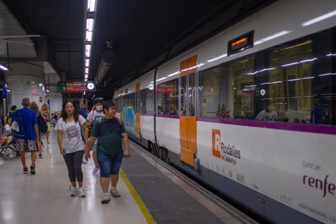 Archivo - Viajeros al lado de un tren en uno de los andenes de la estación de Sants, a 9 de septiembre de 2022