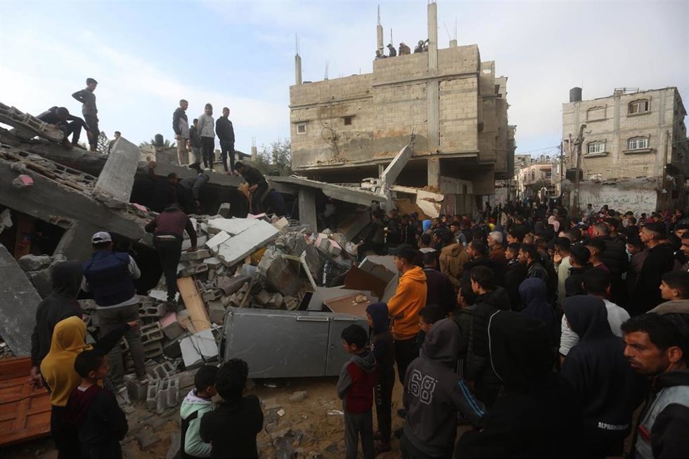 Un grupo de palestinos entre los restos de un edificio destruido por un bombardeo del Ejército de Israel contra la ciudad de Rafá, en el sur de la Franja de Gaza