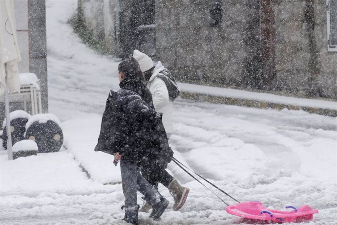 Archivo - Dos personas caminan con un trineo por la nieve, a 18 de enero de 2023, en Castroverde, Lugo, Galicia (España). La cota de nieve está en 400 metros y ha sido acompañada por un descenso de las temperaturas. La situación más complicada está en las