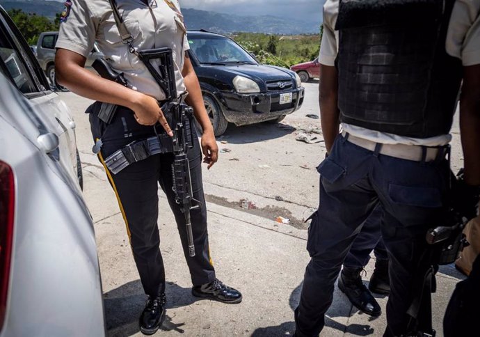 Archivo - January 30, 2024: A heavily armed Haitian policewoman keeps watch as Commissioner Livenston Gauthier (not pictured) talks to some young police officers at a checkpoint near the U.S. Embassy in Port-au-Prince on June 23, 2022.