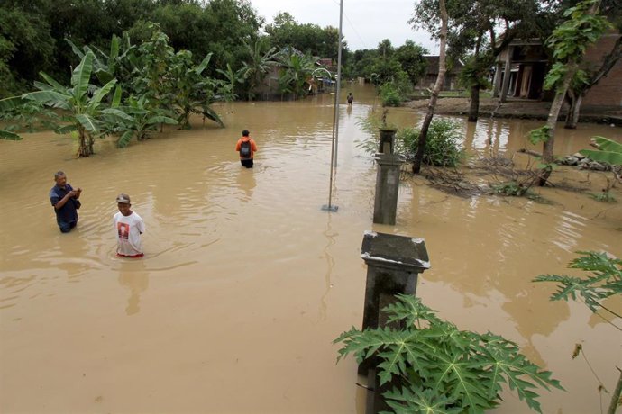 Un grupo de personas vadea las aguas tras las inundaciones en la localidad de Pandak, en Java Central, Indonesia