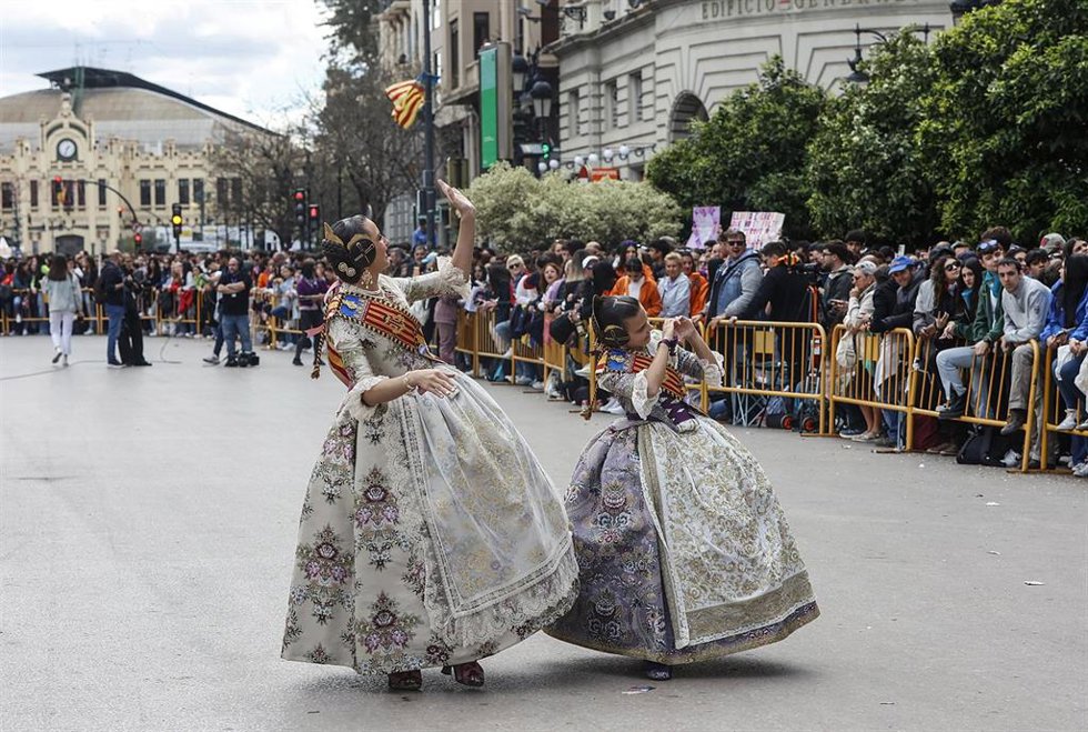 Dos falleras saludan durante una masclet de las Fallas 2024