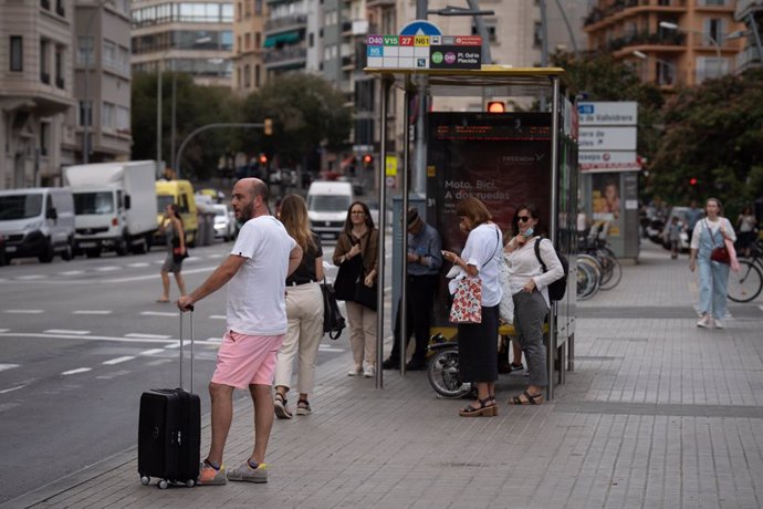 Archivo - Diverses persones en una parada d'autobús