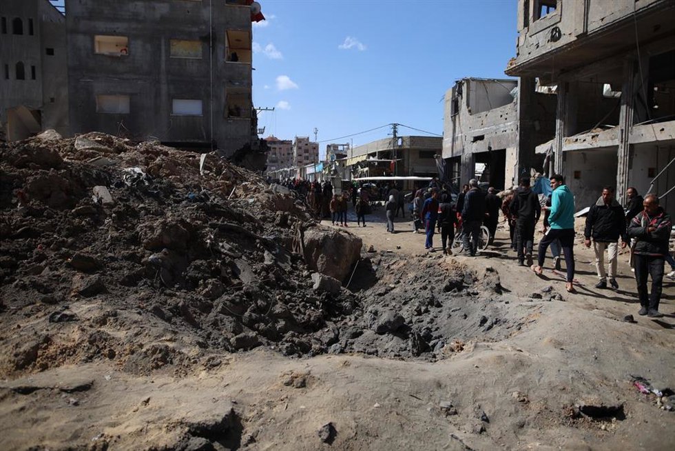 Un grupo de palestinos cerca de un lugar bombardeado por el Ejército de Israel en el campamento de refugiados de Nuseirat, en el centro de la Franja de Gaza