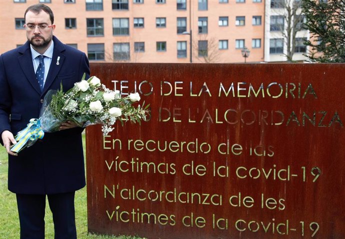 En la imagen, el presidente del Principado, Adrián Barbón, posa con un ramo de flores junto al Tejo de la Memoria, en homenaje a las víctimas de la Covid 19.