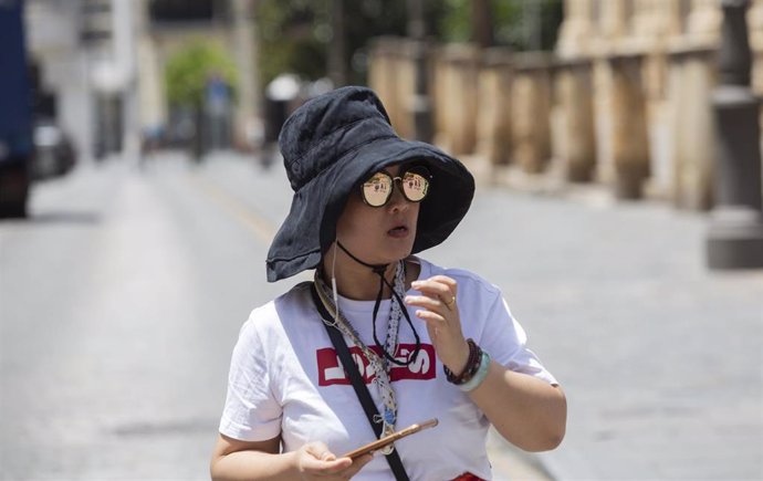 Archivo - Una turista se protege del sol con un sombrero.