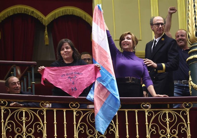 Archivo - La presidenta de Euforia Familias Trans-Aliadas, Natalia Aventín (i), y la presidenta de la Federación Plataforma Trans, Mar Cambrollé (2i), con una bandera trans, durante una sesión plenaria, en el Congreso de los Diputados.