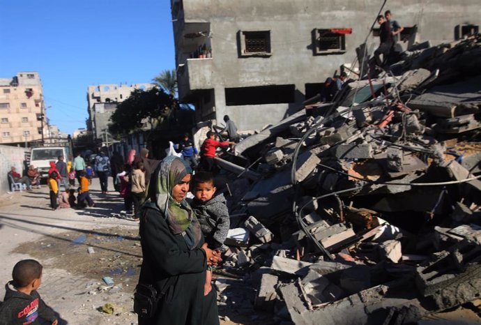 Varios palestinos frente a un edificio destruido por un bombardeo del Ejército de Israel contra la ciudad de Rafá, en el sur de la Franja de Gaza