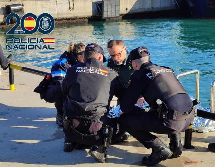Agentes de la Policía Nacional atienden al conductor de un vehículo que cayó al agua en el Puerto de Algeciras.