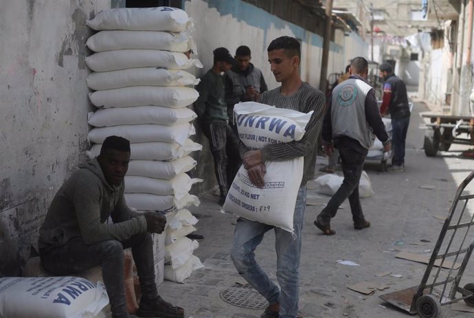 Archivo - Un trabajador palestino transporta un saco de harina de la Agencia de Naciones Unidas para los Refugiados de Palestina en Oriente Próximo (UNRWA) a un campamento de refugiados en la ciudad de Rafá, en el sur de la Franja de Gaza (archivo)