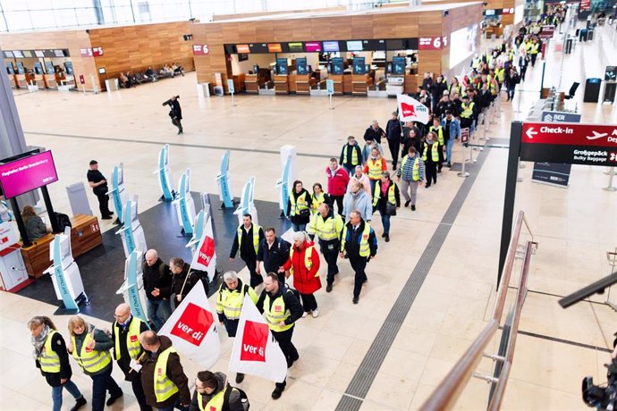 14 March 2024, Berlin, Schoenefeld: Aviation security staff demonstrate with flags in the departure hall in Terminal 1 at Berlin Brandenburg Airport. 
