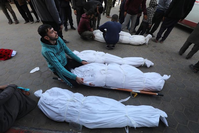 Un hombre vela el cuerpo de sus familiares muertos frente a las puertas de un hospital en Gaza.