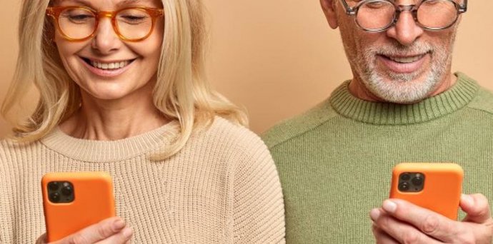 Dos personas mayores de 65 años mirando el móvil