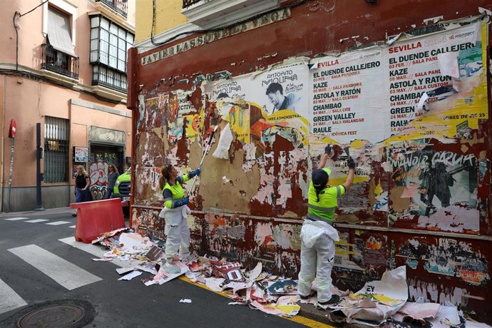 Operarios de Lipasam retiran carteles y adhesivos de un pared del Casco antiguo.