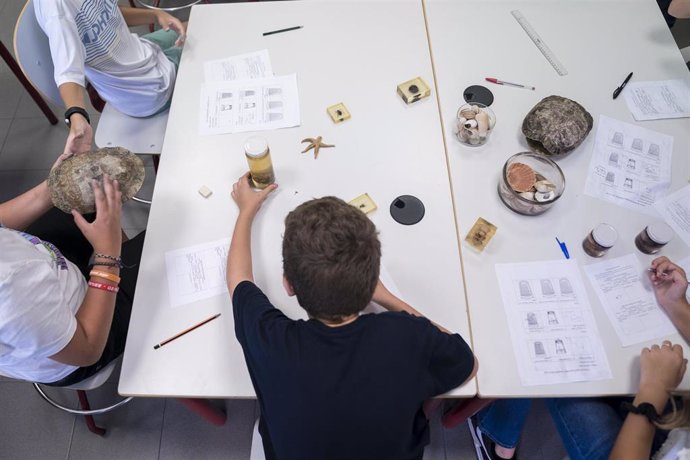 Archivo - Un niño en una mesa de un aula con distinto material escolar.