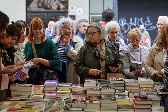 Varias personas miran libros en un puesto instalado por el Día del Libro.